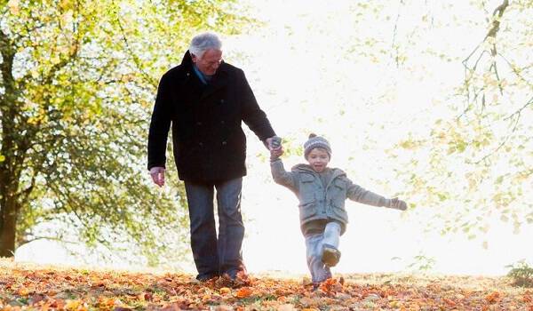 Grandfather walking outdoors with grandson in autumn